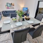 Esstisch mit Stühlen, Sofa und Fernseher im Wohnbereich.