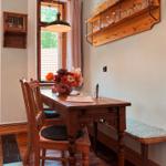 Holztisch mit Stühlen und Bänken, Wandregal mit Gläsern, Fenster mit Vorhang.