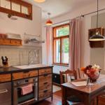 Küche mit Essbereich, Holzmöbel und Fenster mit rosa Vorhängen.