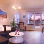 Wohnzimmer mit Sofa, zwei Sessel und Tisch. An der Wand hängt ein Strandbild.