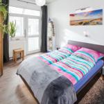 Schlafzimmer mit Bett, Nachttisch, Kleiderschrank und Fenster.