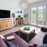 Wohnzimmer mit Sofa, Fernseher und Glastür zur Terrasse.