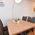 Esszimmer mit Holztisch, vier Stühlen und Wanddekoration.