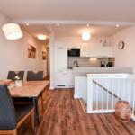 Essbereich mit Tisch und Stühlen, Küche mit Arbeitsplatte und Küchenschränken, Boden aus Holz