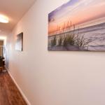 Flur mit Holzboden und Wandbildern, Sicht in Essbereich mit Tisch und Stühlen.