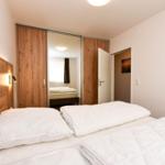 Schlafzimmer mit Doppelbett, Holzschrank und Nachttischbeleuchtung.