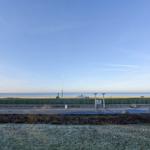 Meeresblick mit Promenade und frostigem Gras im Vordergrund.