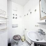 Badezimmer mit Waschbecken, Toilette und Dusche. Weiße Fliesen und Spiegel.