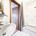 Badezimmer mit Badewanne, Duschkopf und Waschbecken mit Spiegel.