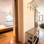 Schlafzimmer mit Bett und Fenster. Flur mit Garderobe und Tisch. Wohnzimmer mit Sofa.