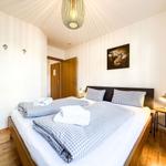 Schlafzimmer mit Bett, Decke und Kissen. Wandbild und Nachttisch mit Lampe.