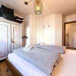 Zimmer mit Doppelbett, Kleiderschrank und Decken. Decke mit Lampe und Tür.