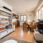 Küche mit Essbereich und Wohnzimmer mit Fernseher und Holzboden.