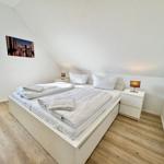 Schlafzimmer mit Dachschrägen, weißem Bett und Nachttischen.