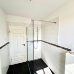 Badezimmer mit Dusche, Heizung und Waschtisch mit Segelschiffdekoration.