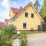 Ein gelbes Haus mit rotem Dach, umgeben von Grün und einem gepflasterten Weg.