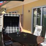Terrasse mit Tisch, Stühlen und Schirm. Hintergrund: Haus mit Schiebetür.