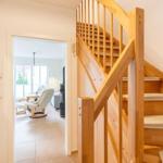 Holztreppe mit Teppichstufen führt zu einer offenen Wohnfläche mit Sitzgelegenheit.