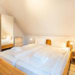 Schlafzimmer mit Doppelbett, Nachttischen und Spiegelschrank unter schrägem Dach