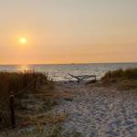 Sandweg führt durch Dünen zum Meer bei Sonnenuntergang.