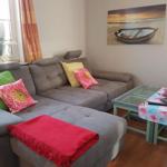 Ein Wohnzimmer mit grauem Sofa, Glas-Tisch und Wandbild mit Boot.