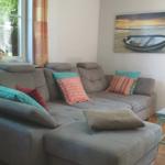 Großes Sofa mit Kissen, Wandbild und Fenster mit Blick nach draußen.