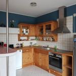 Küche mit Holzschränken, Edelstahlherd und Kühlschrank