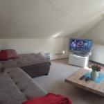 Wohnzimmer mit Schlafcouch, Fernseher und Holztisch unter schrägen Dachschrägen.