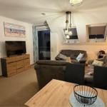 Wohnbereich mit Sofa, Fernseher und Tisch. Dachfenster und Balkontür.