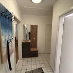 Flur mit Garderobe, Spiegel und Holzpaneelen. Weiße Wände und Fliesenboden.