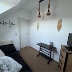 Schlafzimmer mit Dachschrägen, Bett, TV-Schrank und Hängelampen.