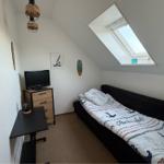 Schlafzimmer mit Dachschrägen, Dachfenster, Bett und Schreibtisch.