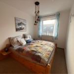 Schlafzimmer mit Holzbett, Fenster mit Vorhängen und Wandbild mit Boot.