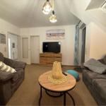 Wohnzimmer mit zwei Sofas, runden Tisch und Fernseher an der Wand.