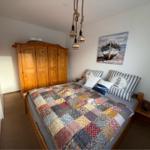 Schlafzimmer mit Holzbett, Kleiderschrank und Wandbild mit Boot.