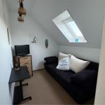 Schlafzimmer mit Sofa, TV und Dachfenster. Wanddekoration und schlichte Einrichtung.