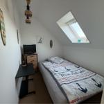 Schlafzimmer mit Dachschrägen, Bett mit Ankern-Motiv, TV und Schreibtisch.