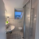 Badezimmer mit Dusche, Waschbecken und Toilette. Dachfenster mit Segelbootdekoration.