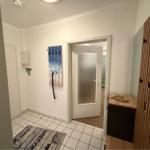 Eingangsbereich mit Fliesenboden, Holzgarderobe und Wandhaken mit Strandmotiv.