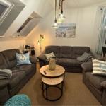 Wohnzimmer mit zwei Sofas, runden Tischen und Fenstern. Wandbild und Deckenleuchten.