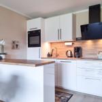 Küche mit weißen Schränken, Holzoberfläche und integriertem Backofen.