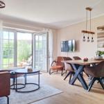 Wohn- und Essbereich mit Holzboden, Esstisch, TV und Terrassentür.