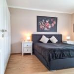 Schlafzimmer mit Bett, Nachttischen und Wandbildern