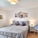 Schlafzimmer mit Bett, Nachttischen und Wandbildern.