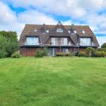 Haus mit braunem Dach und grünem Garten unter blauem Himmel.