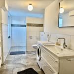 Badezimmer mit Dusche, Waschmaschine und Spiegel