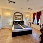 Schlafzimmer mit Doppelbett, roten Vorhängen und Holzboden.