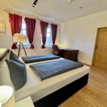 Schlafzimmer mit Doppelbett, roten Vorhängen und Holzboden.