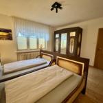 Zwei Betten, Schrank, Fenster mit Jalousien und Tür mit Glasfenstern.