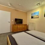 Schlafzimmer mit Doppelbett, Holzschrank und Fernseher an der Wand.